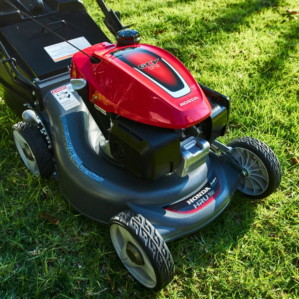 Red push lawnmower on green grass